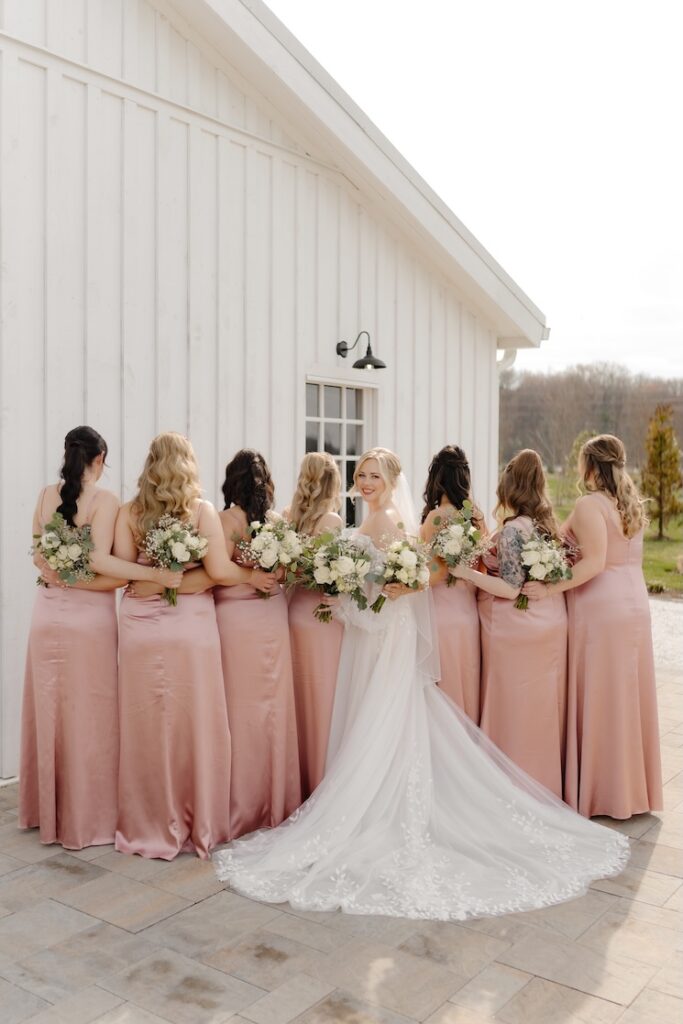 Bridesmaids looking away from camera, while bride is looking at the camera, and they are holding green and white small delicate bouquets by Winters Farm Florals